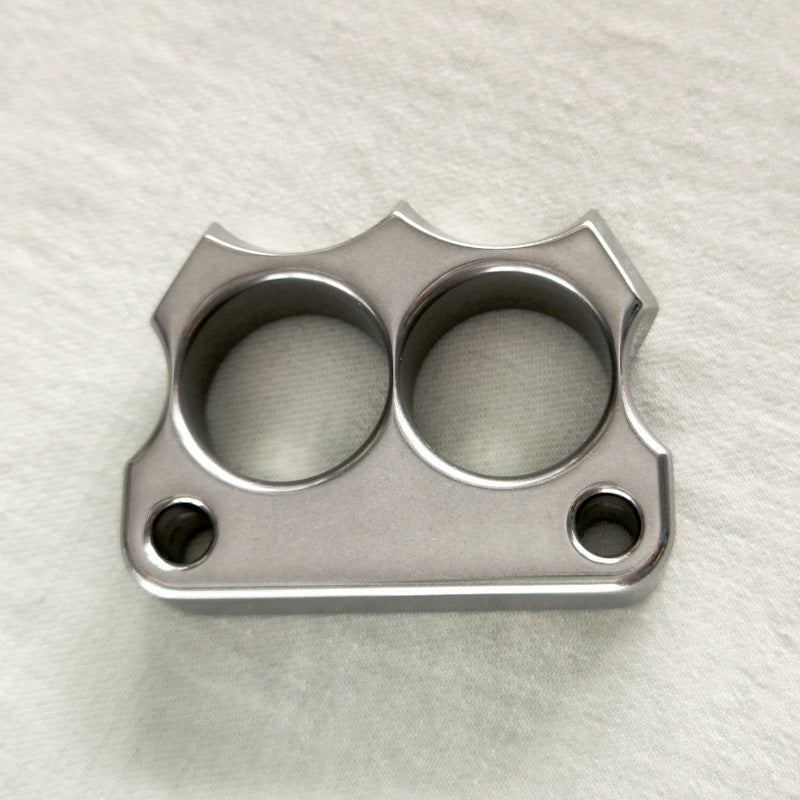 Top-down view of the mirror polished 316 steel two-hole mini duster on a light fabric surface.