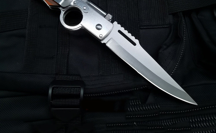 Close-up of stainless steel blade and finger-hole frame on black tactical fabric