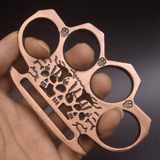 Rose gold skeleton knuckle duster worn on the fingers showing the skull artwork and palm-edge slot