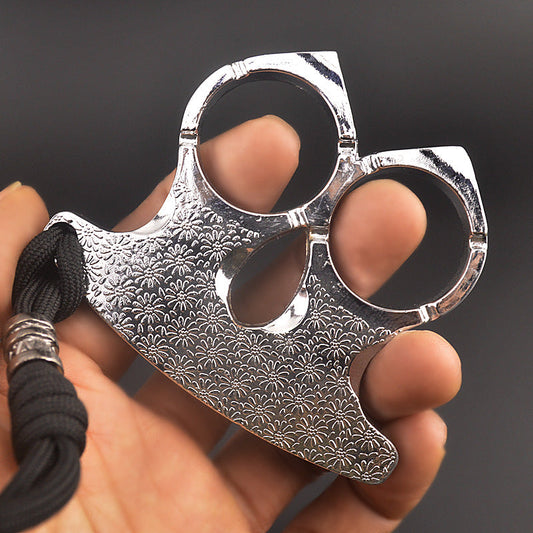 Silver two-finger knuckle held between fingers, polished ring edges and engraved flowers in view