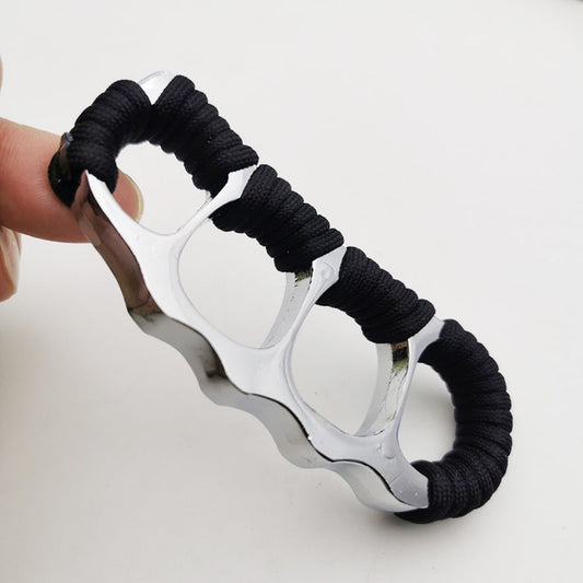 Silver zinc alloy knuckle duster held in hand, black paracord coils along the upper edge
