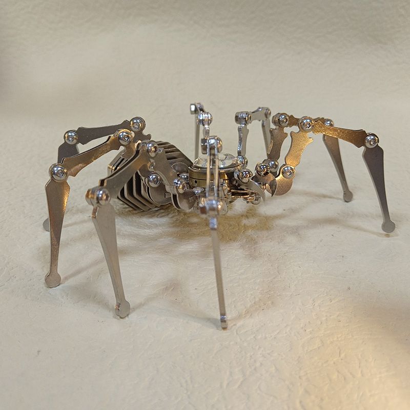 Side profile of the stainless steel spider sculpture standing on a cream leather surface