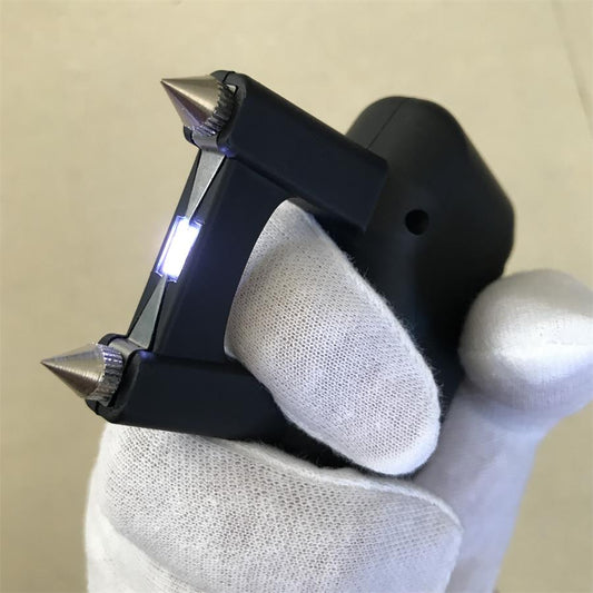 Hand in a white glove holding the matte black stun device with the electrode prongs pointing left.