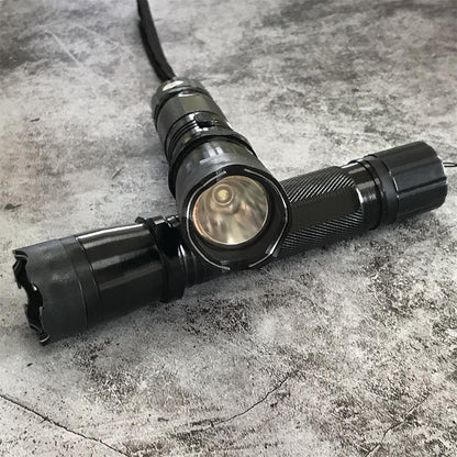 Two black 1101 flashlight stun guns crossed showing side switch and textured aluminum body