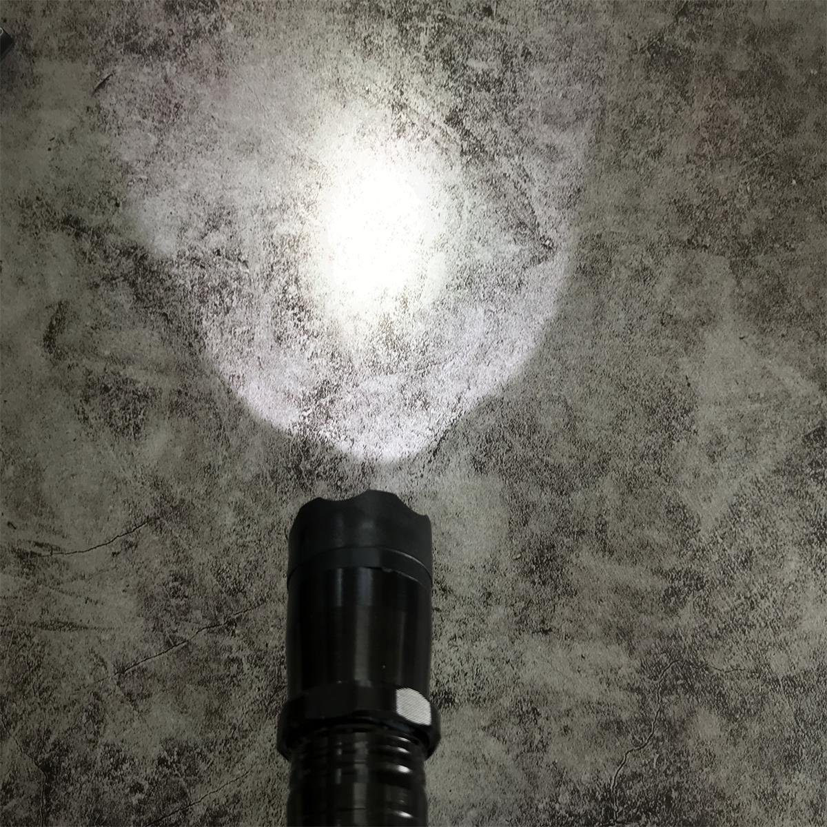 Black 1101 flashlight stun gun shining bright white LED beam on concrete floor
