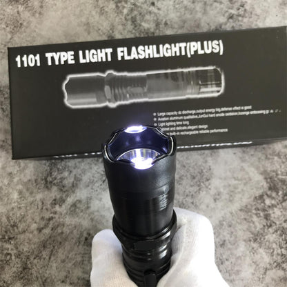 Hand holding black 1101 flashlight stun gun with LED illuminated in front of product box