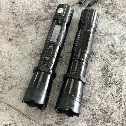 Two black 1101 flashlight stun guns lying parallel showing front bezels and switches