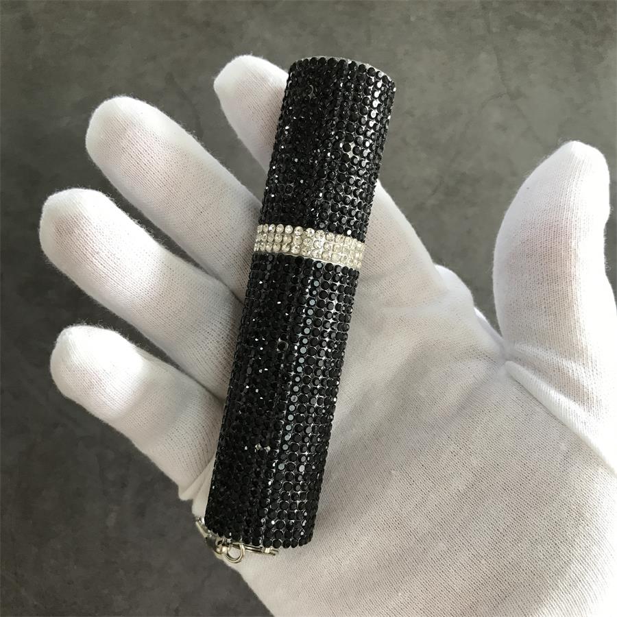 Hand holding closed black rhinestone mini stun gun with silver crystal band and keychain