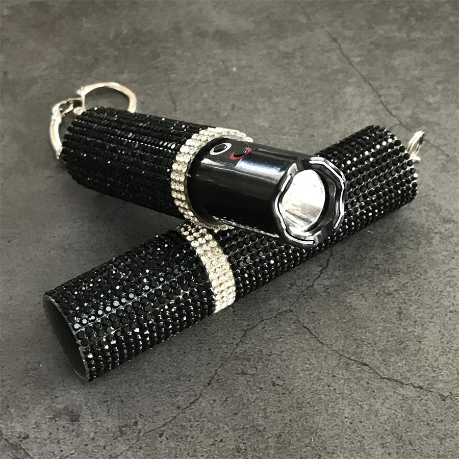 Two black crystal-studded mini stun guns crossed showing flashlight bezels and key rings