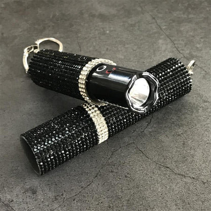 Two black crystal-studded mini stun guns crossed showing flashlight bezels and key rings