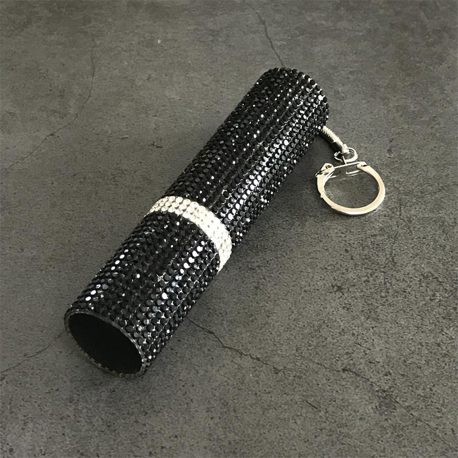 Black rhinestone mini stun gun with keychain lying on gray concrete surface