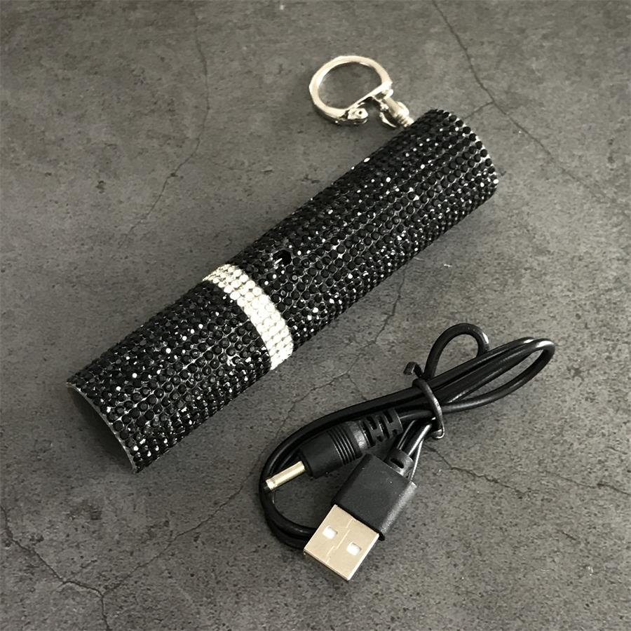 Black rhinestone mini stun gun with USB charging cable and keychain on gray surface