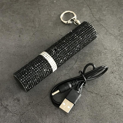 Black rhinestone mini stun gun with USB charging cable and keychain on gray surface