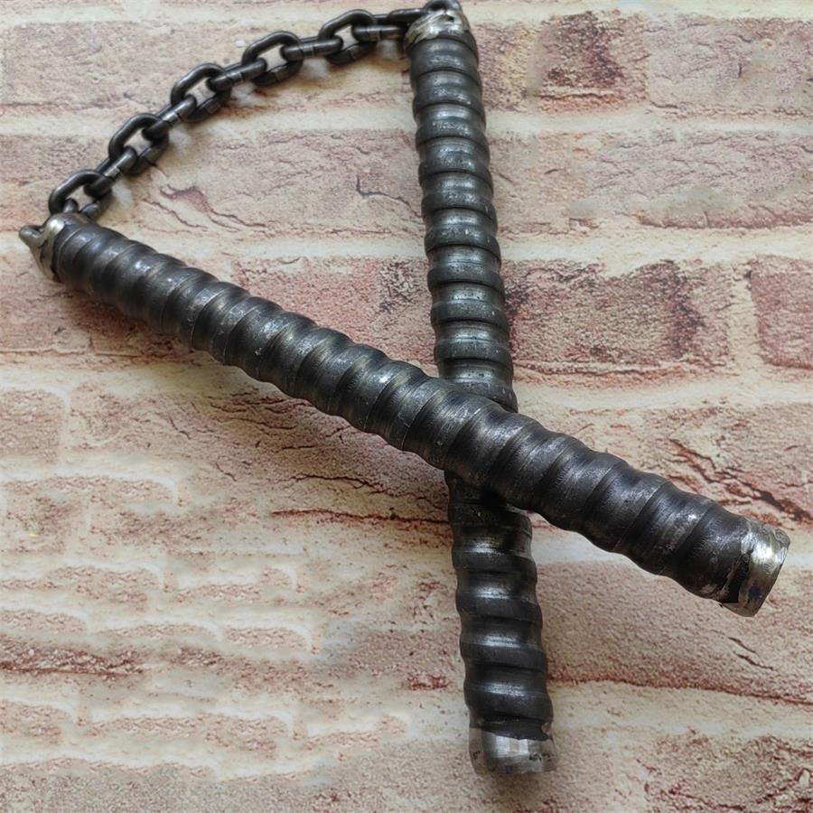 Two black rubber-wrapped chain baton handles crossed on brick-pattern background