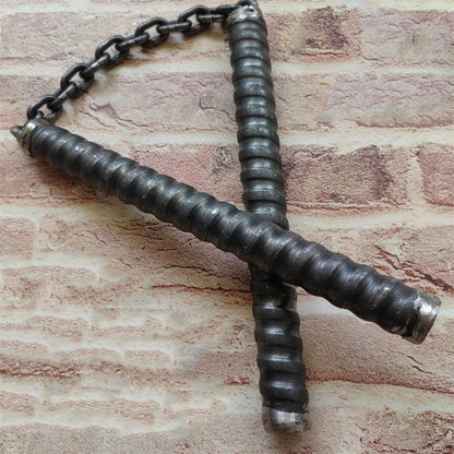 Two black rubber-wrapped chain baton handles crossed on brick-pattern background