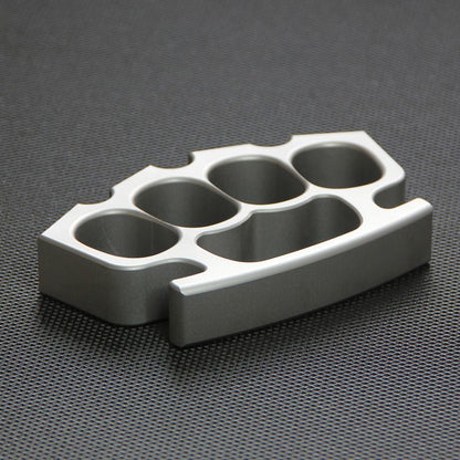 Silver knuckle duster lying flat on black textured surface, palm-side facing up.