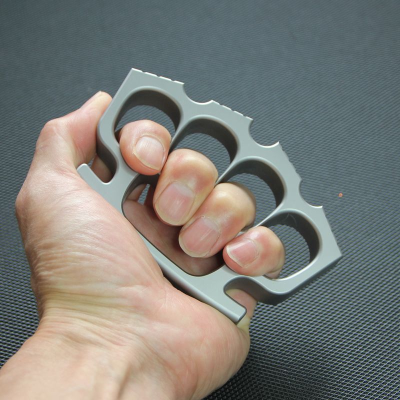Fingers inserted through the four holes of the silver knuckle duster, grip demonstration.