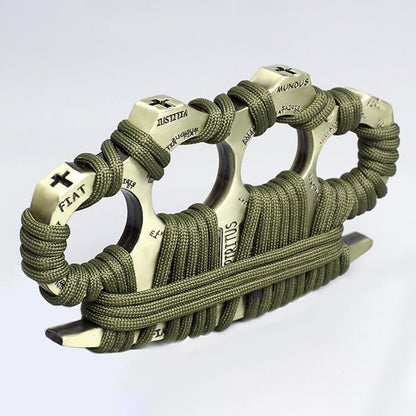 Close-up of a Bronze zinc alloy knuckle duster wrapped in olive-green paracord, with Latin words including FIAT, JUSTITIA and MUNDUS embossed on the four knuckle faces and a cross motif at the outer edge, against a plain background.