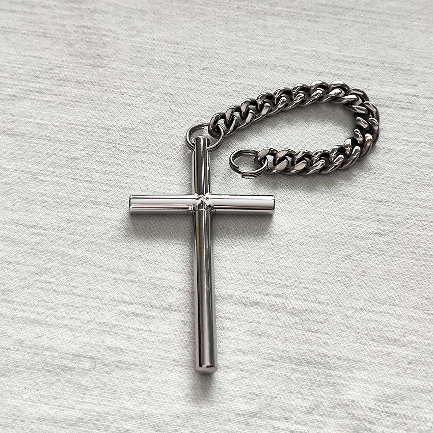 The 304 steel cross toothpick and pure titanium chain laid flat on a light textured surface.