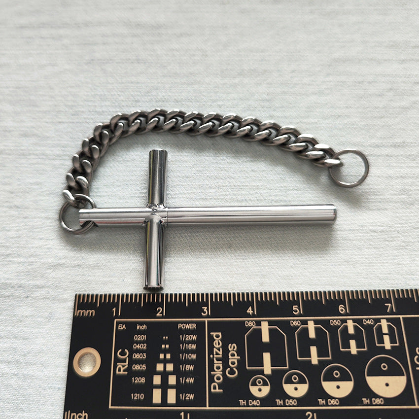 304 steel cross toothpick and titanium chain placed above a black PCB ruler showing scale.