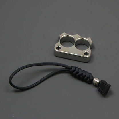 316 steel two-hole mini duster placed next to its black paracord lanyard on a grey surface.