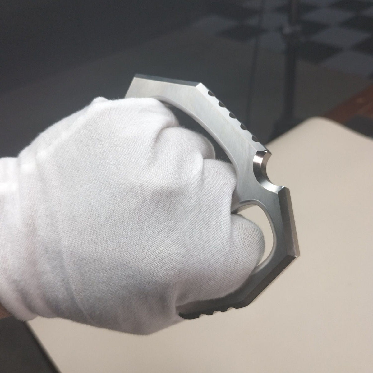 Side view of the white-gloved fist holding the two-finger rope hole duster.