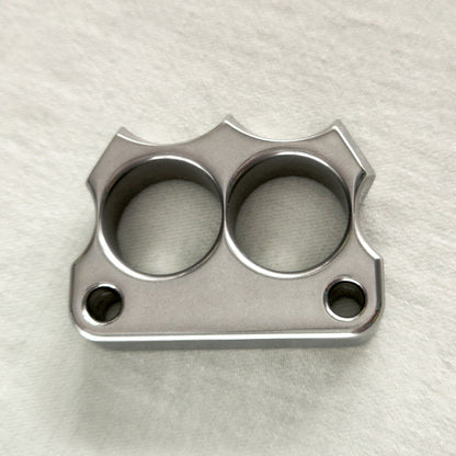 Top-down view of the mirror polished 316 steel two-hole mini duster on a light fabric surface.