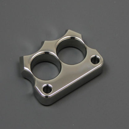Mirror polished 316 stainless steel two-hole mini knuckle duster lying on a dark grey surface, top view.