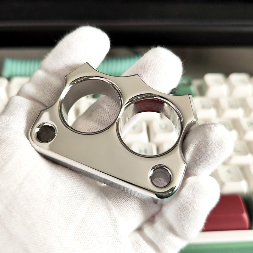 White-gloved hand holding the mirror polished 316 steel two-hole mini duster above a mechanical keyboard.