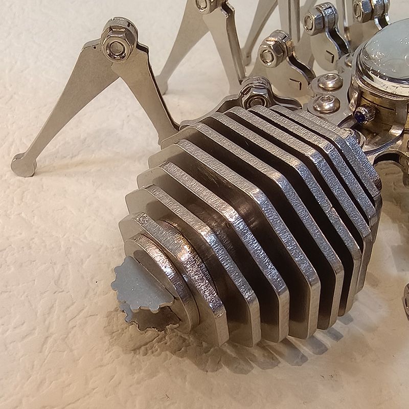 Side close-up of layered steel abdomen segments with a gear-toothed tail detail