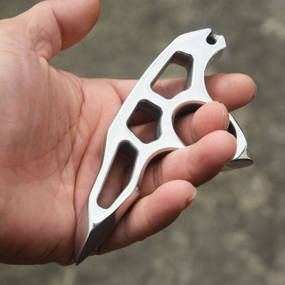 Angled top view of the mirror-polished steel knuckle duster in an open palm with a finger through the round hole