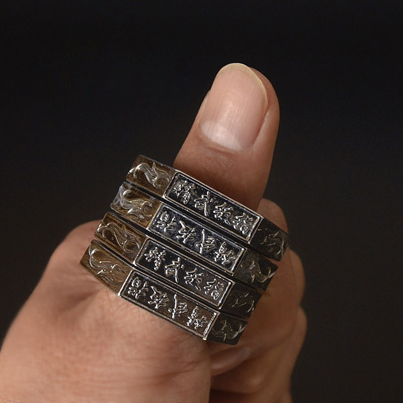 Antique silver stacked hexagon rings worn on a finger showing engraved characters and flame motifs on each band