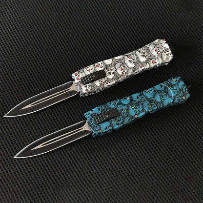 White skull and blue floral OTF knives crossed on black surface