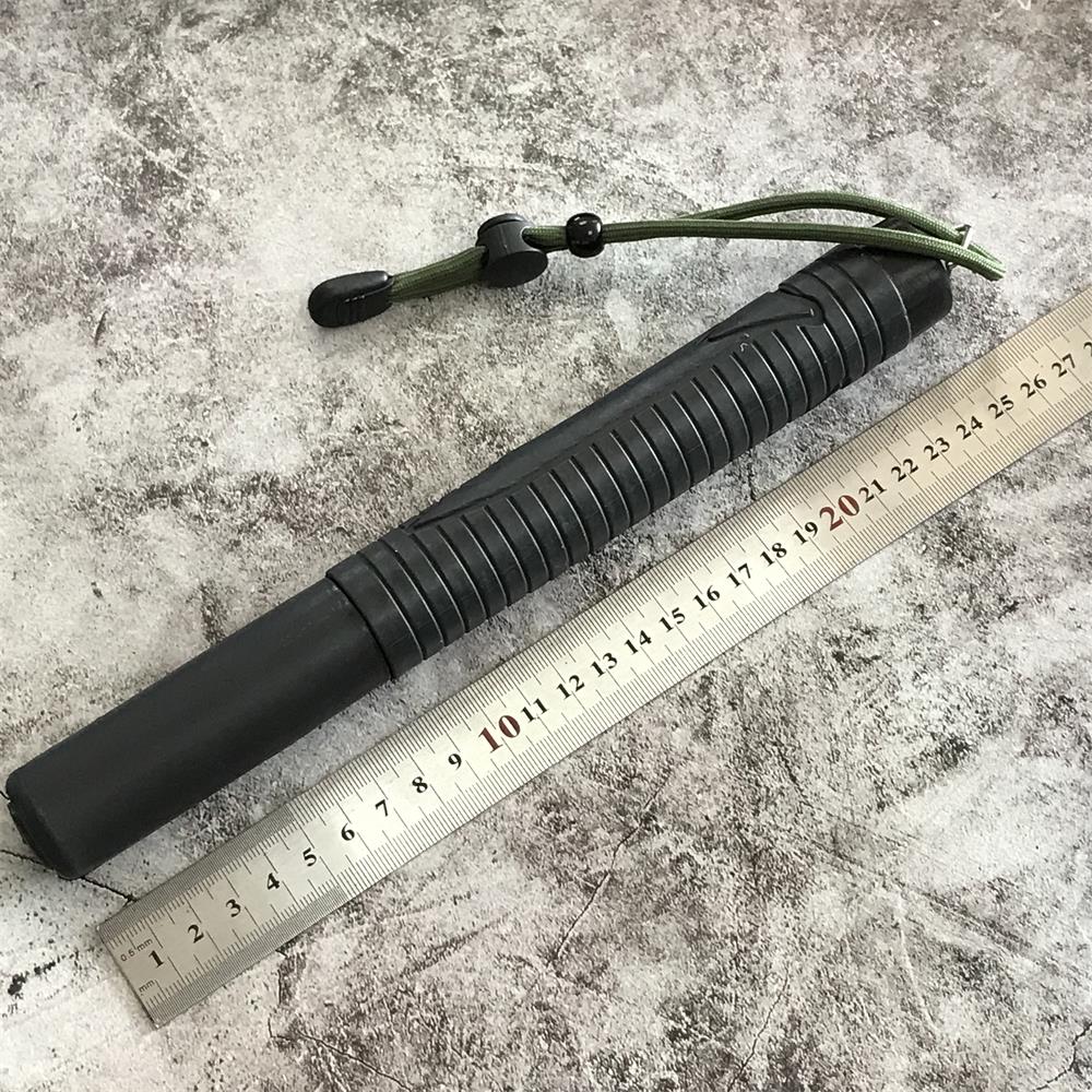 Collapsed black baton with ribbed handle beside a ruler on a concrete floor