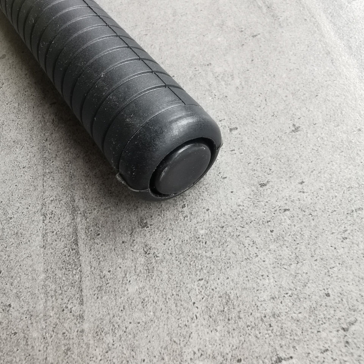 Macro view of the smooth dome cap on the ribbed rubber handle of the baton