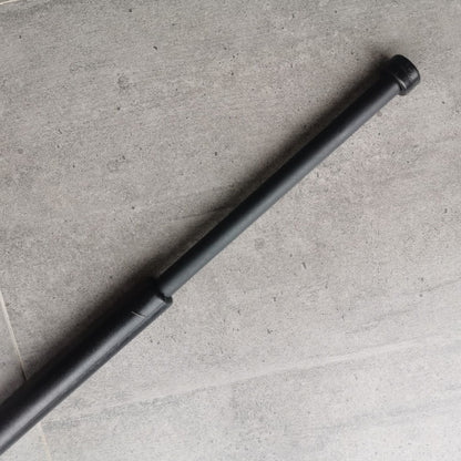 Black baton extended diagonally across a concrete floor with the thin shaft out