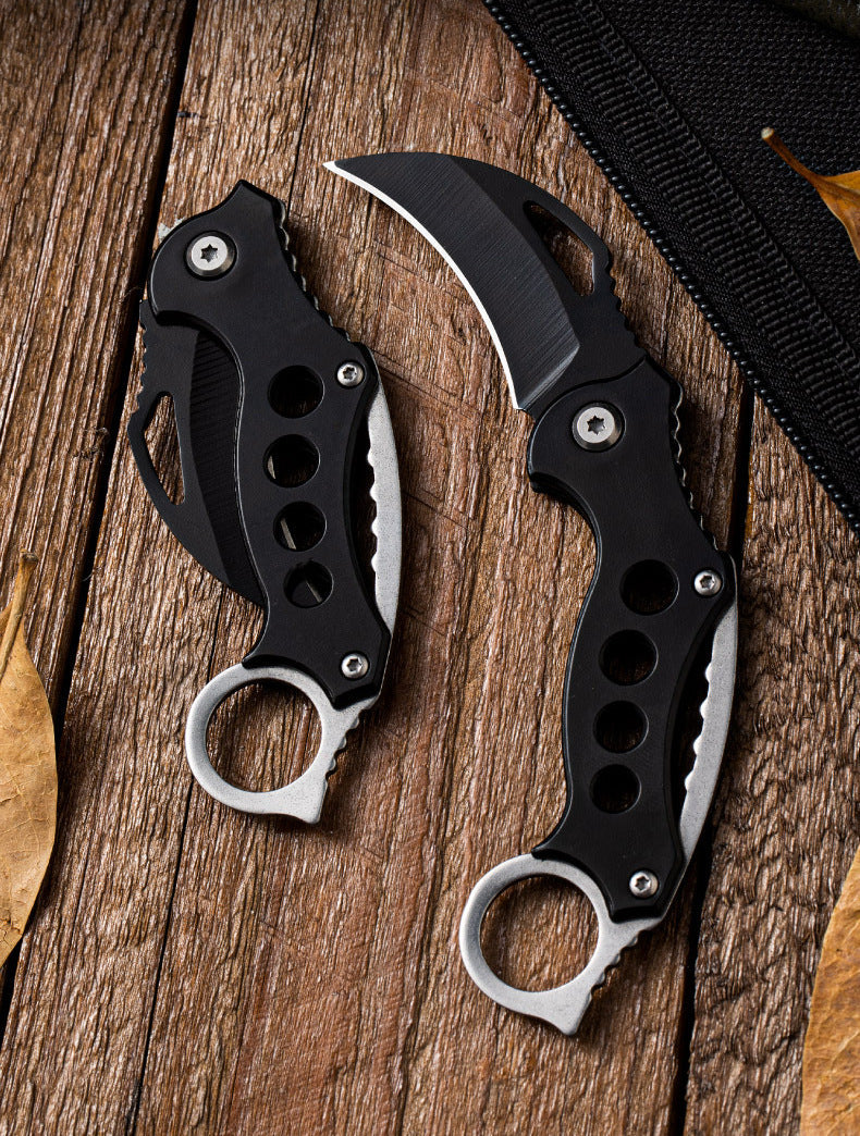 Pair of Black Bird claw knives on wood beside a black zip pouch, one open and one closed.