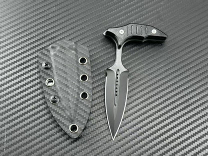 Black blade push dagger next to its carbon fiber sheath on textured background