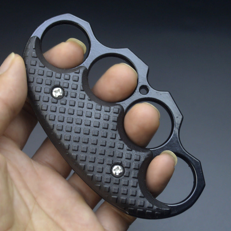 All-black covered EDC knuckle duster held in a hand, showing the textured grip panels.