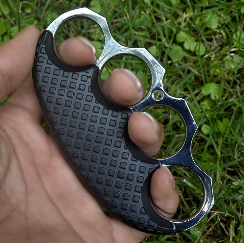 Rose Gold-ring black-covered knuckle duster laid flat on black fabric.