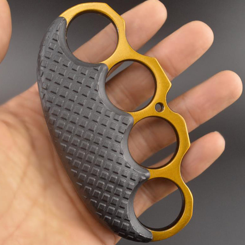 Silver-ring black-covered knuckle duster held outdoors over green grass.