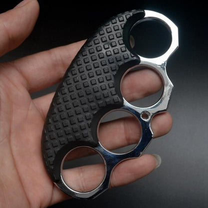 Silver-ring black-covered knuckle duster held in a hand against a dark background.