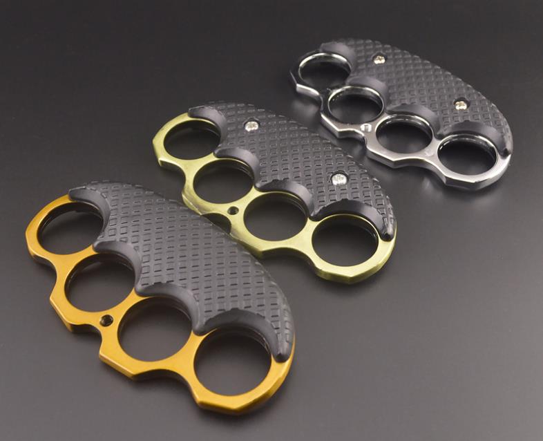 Five black-covered EDC knuckle dusters in Gold, Silver, Bronze, Black and Rose Gold laid on a dark surface.