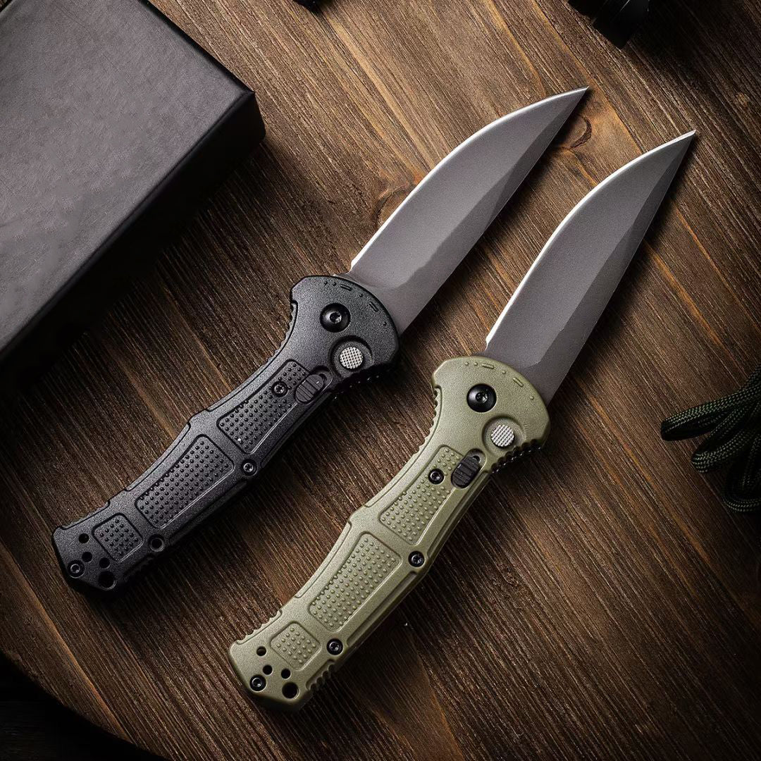 Black and green folding knives standing open on a dark wooden table
