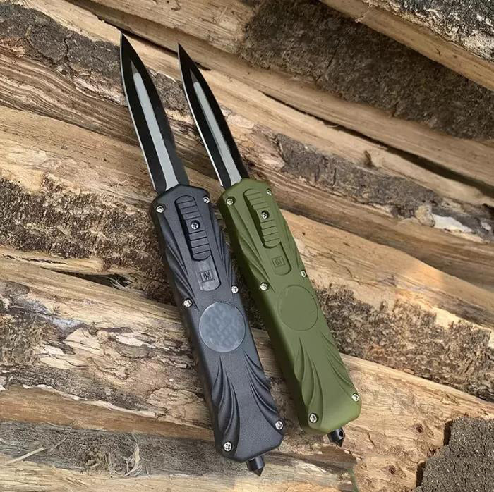 Black and green automatic OTF pocket knives side by side on wooden logs