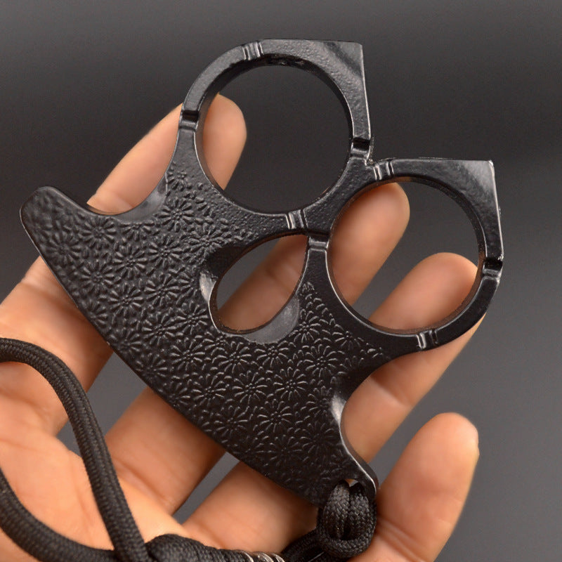 Matte black two-finger knuckle held in an open palm, embossed floral pattern across the plate