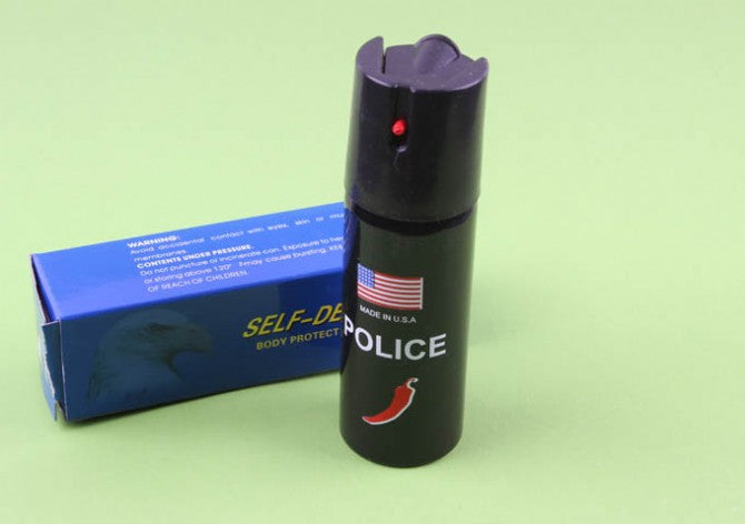 Black 60ml pepper spray canister with POLICE label standing beside blue box