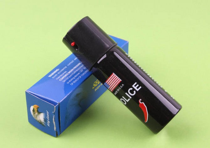 Black POLICE pepper spray canister leaning against blue packaging box