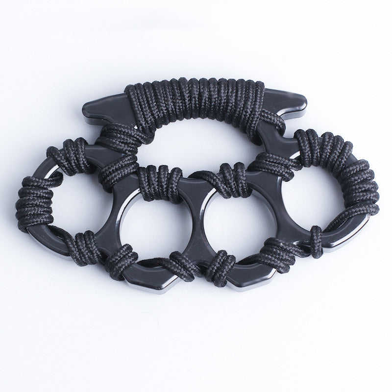 Top-down view of the black woven knuckle duster showing the umbrella rope knots around all four openings and the wrapped grip