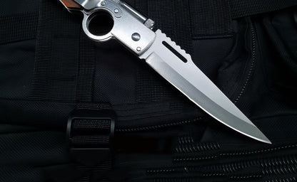 Close-up of stainless steel blade and finger-hole frame on black tactical fabric